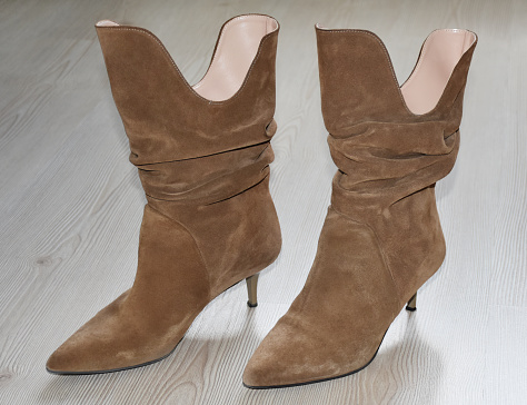 Suede leather elegance female boots on the wood floor