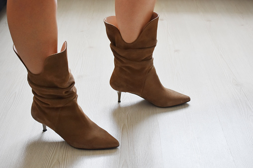Women's legs in the boots with indoor wood floor