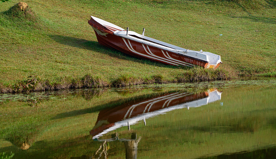 Motorboat on the shore and its reflection on the waters of Hiyare resovior.