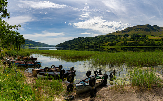 Glencar, Ireland - 16 July, 2022: Glencar Lough landscape with many colorful small wooden fishing boats on the lakeside