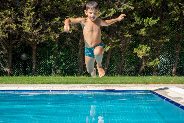 istock Little Rascal Boy is Enjoy Swimming In The Pool While Jumping Into Thje Water 1410423936