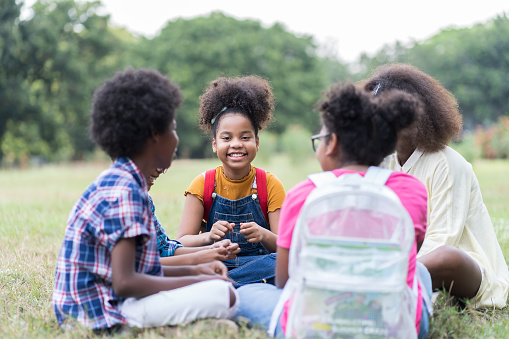Grupo de niños afroamericanos aprendiendo y escribiendo libros en el parque. Niño y niña sentados y aprendiendo fuera del aula. Excursiones para niños afuera. Los niños y el concepto educativo photo
