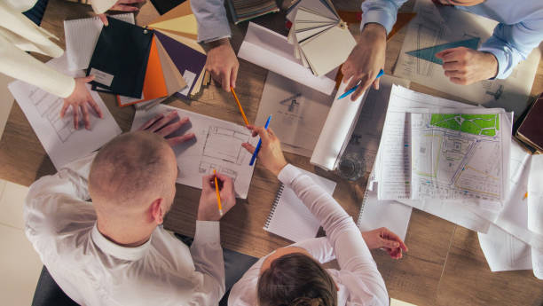 istock Group of architects analyzing blueprints and sketching new ideas during a meeting 1410424983