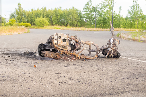 Newburn England: 16.06.2022: stolen motorbike set on fire burned out and abandoned on industrial estate Road with green trees