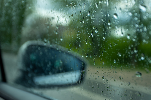 Close-up shot of rain drops on the side window of the car