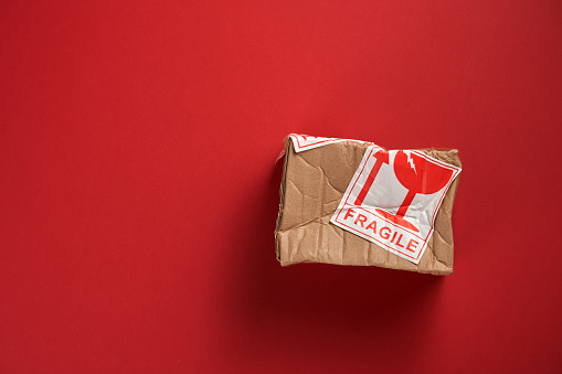 Damaged cardboard box isolated on red