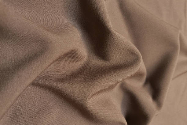 istock Beige or brown crumpled or wavy fabric texture background. Abstract linen cloth soft waves. Silk atlas or stretch jacquard. Smooth elegant luxury cloth texture. Concept for banner or advertisement 1410428066