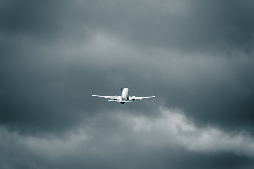 Passenger aircraft flying in the cloudy sky after take off. Heavy cumulonimbus clouds in the flight. Bussiness trip. Adventure and journey concept.