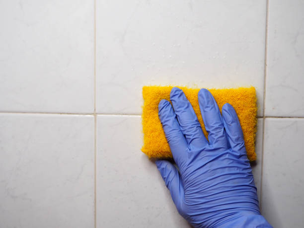 istock Hand holds a sponge against a tiled wall 1410428370