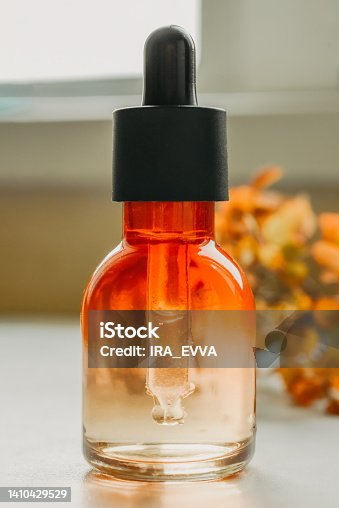 istock Serum with hyaluronic acid in orange bottle with pipette close-up. Spa and bio autumn skincare concept 1410429529