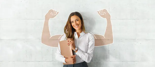 Beautiful business woman with smile and a laptop in her hands in the office near a white wall with blank space for text