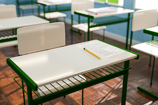 From above paper with test tasks and pencil placed on desk in sunlit classroom. 3d render