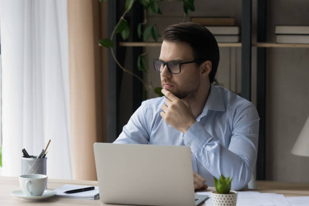 istock Pensive smart young businessman working on computer. 1410433640