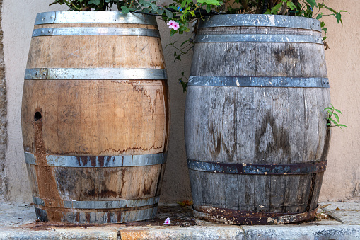 A rustic, wooden barrel-shaped table stands atop a brick patio in a sunny outdoor setting