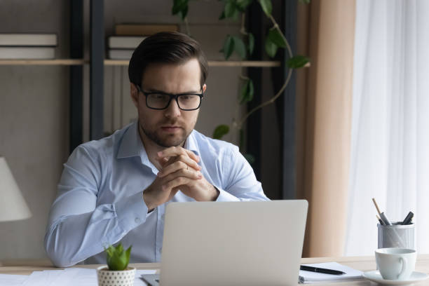 istock Pensive young businessman in glasses working on computer. 1410435345