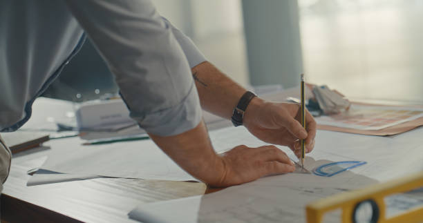 istock Closeup of architect hands drawing or designing blueprint building plan. Professional architectural engineer or contractor sketching and measuring home or office rooms. Planning structure development 1410440183