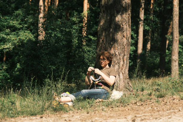 istock Woman is sitting under the tree and knitting 1410442413
