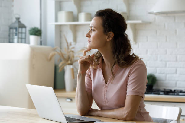 istock Pensive young stressed woman looking in distance, working on computer. 1410442557