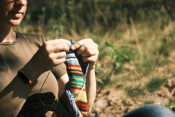 istock Woman is sitting under the tree and knitting 1410442710