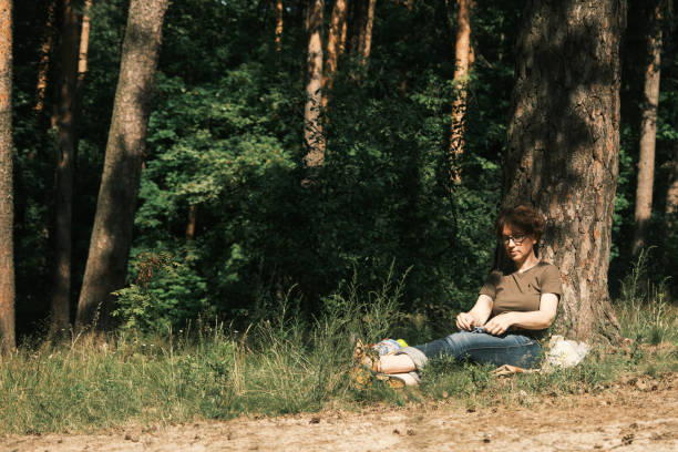 istock Woman is sitting under the tree and knitting 1410442725