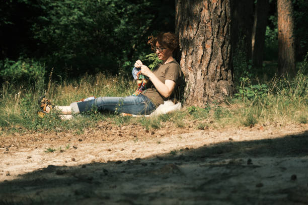 istock Woman is sitting under the tree and knitting 1410442755