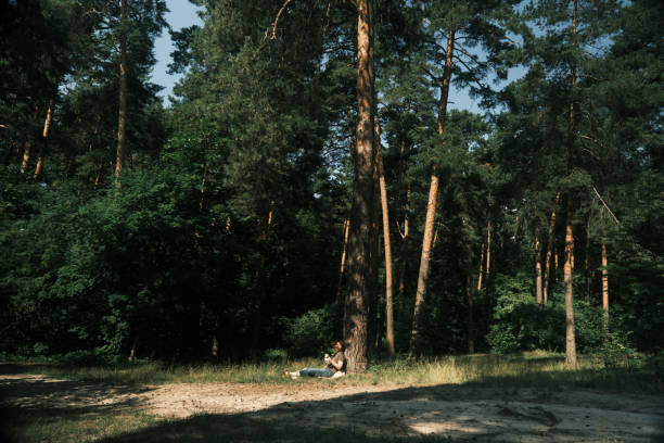 Mature woman is sitting under the tree  in nature park and knitting