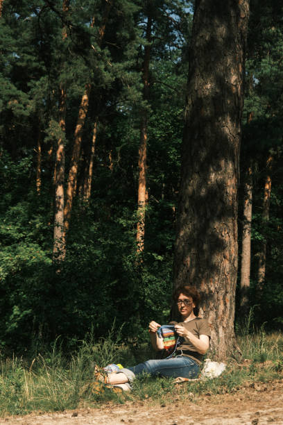 istock Woman is sitting under the tree and knitting 1410442956