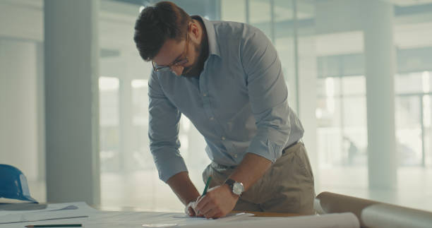 istock Architect drawing or designing blueprint building plans. Professional architectural engineer or contractor sketching or measuring rooms for home or office. Thinking and planning structure development 1410443071