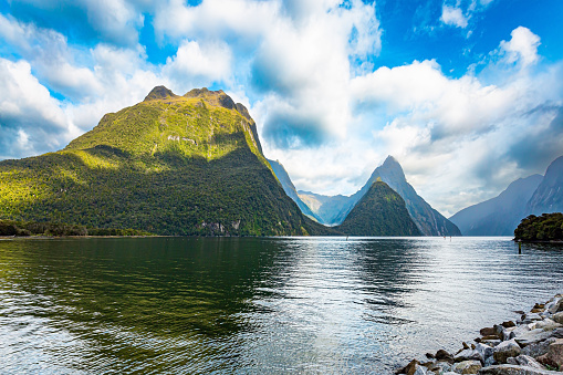 The magical nature of the southern hemisphere. New Zealand. South Island. The picturesque fjord of glacial origin is Milford Sound. The mountains are reflected in the smooth water of the fjord.