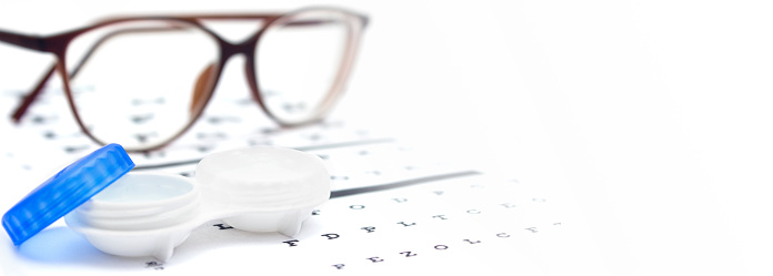 Contact lenses case and eye glasses on and eye test chart. Vision concept. Way to improve vision. Close up. Selective focus. Copy space