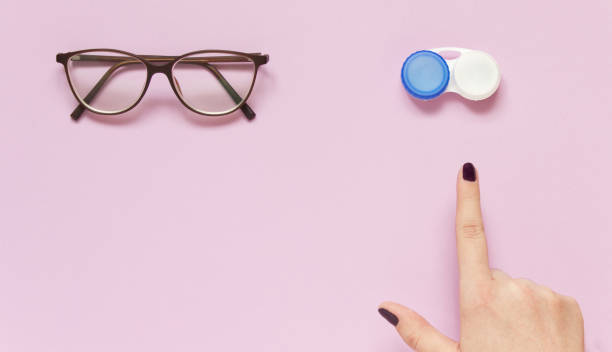 glasses and contact lens case on purple background. human hand indicate on lenses. concept of choice the way vision correction - lens contact lens glasses transparent imagens e fotografias de stock