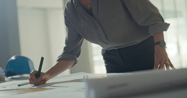 istock A professional architect drawing plans on a table in an office. A creative female professional engineer designing and sketching blueprint plans for building or architectural structures in a office 1410446237