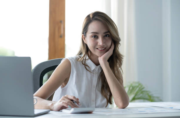 istock Charming Asian woman working at the office using a laptop Looking at the camera. 1410448952