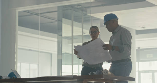 istock Two architects discussing a blueprint in an office. Male and female engineers talking floor plans and architectural plans during a meeting. Partners working on a strategy for a building project 1410449582