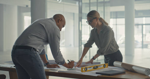 istock Two architects drafting blueprint plans for a building and construction project. Dedicated industrial designers and engineers developing a layout and adjusting measurements for property development 1410450209