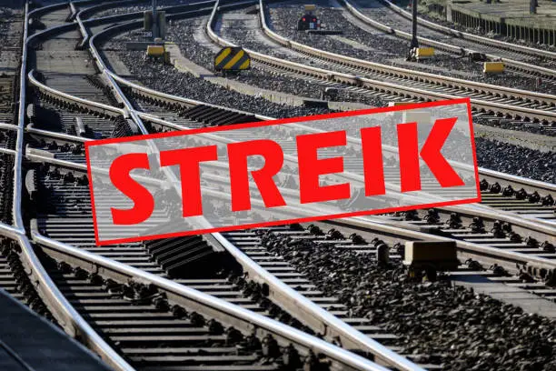 German text Streik (meaning strike) over lots of railroad tracks and switches, trade union concept for fair pay and working conditions in the transport sector, selected focus, narrow depth of field