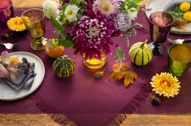 istock Festive table setting for Thanksgiving day. Autumnal decorations,plates, multicolor glasses and beautiful garden flowers. 1410453490