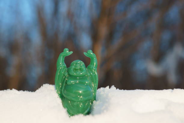 A figure of a green Buddha on a background of snow. Decorative figures of Feng Shui.