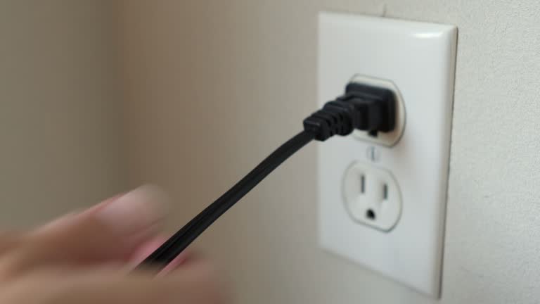 Hand Putting Plug in and Out of Outlet