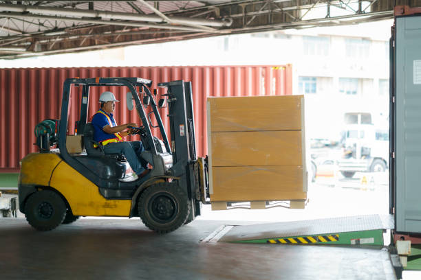 gabelstapler werden in frachtcontainer in lagern, häfen, speditionen, frachtlieferketten, frachttransport, lagerindustrie, logistik verladen. - gabelstapler stock-fotos und bilder