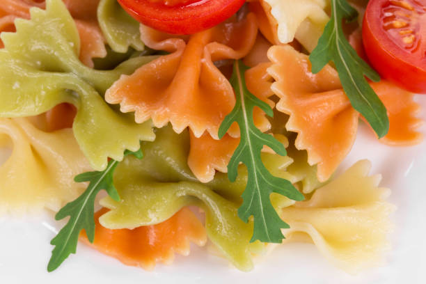 Bunch of the farfalle pasta three colors. Whole background. It is located on a white surface. Close-up.