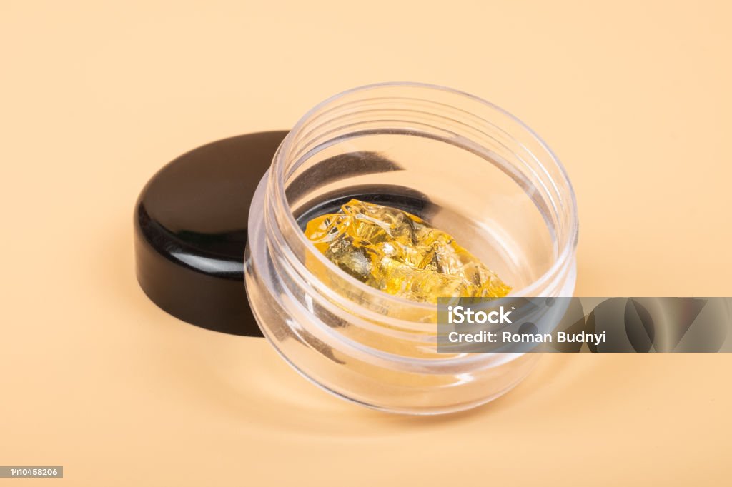 golden cannabis  dab in glass container, wax extract on yellow background golden cannabis  dab in glass container, wax extract on yellow background. Concentration Stock Photo