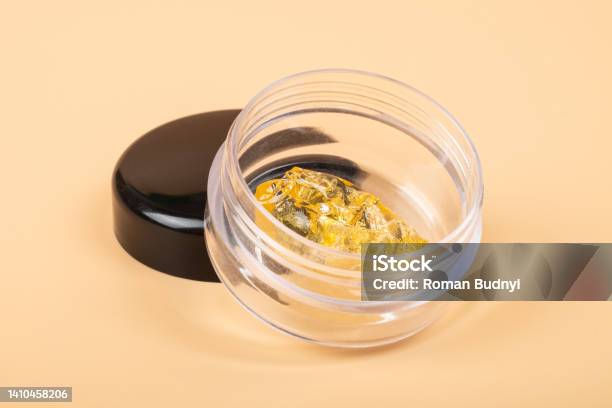 Golden Cannabis Dab In Glass Container Wax Extract On Yellow Background Stock Photo - Download Image Now