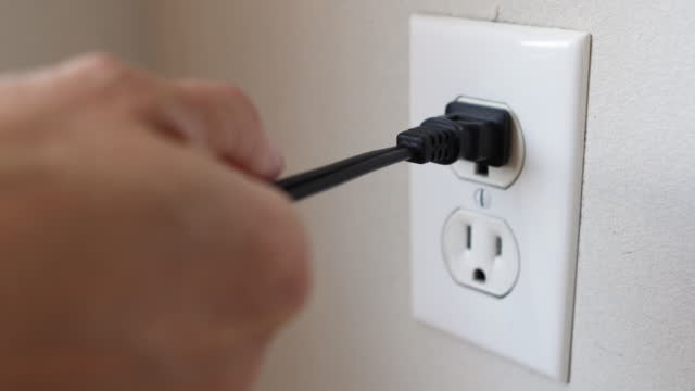 Hand Putting Plug into Electric Outlet and Pulling it Out Wrong
