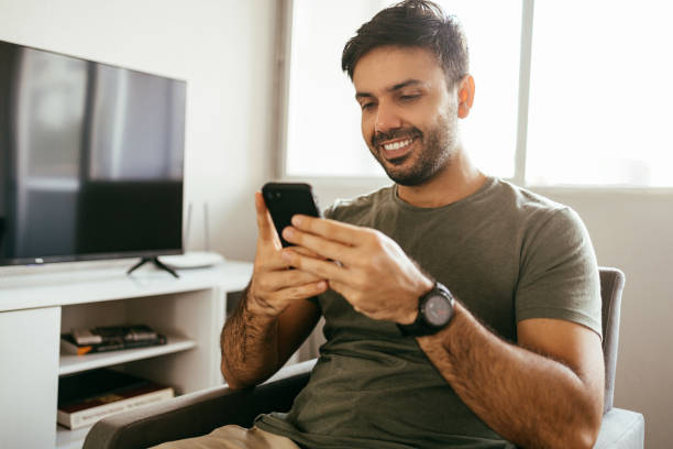 istock Young man using cellphone in the living room 1410462137