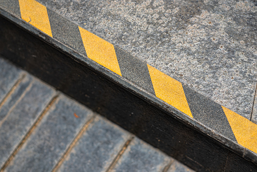 Anti-slip surface with caution strip line on the edge of different level floor. Close-up and selective focus.