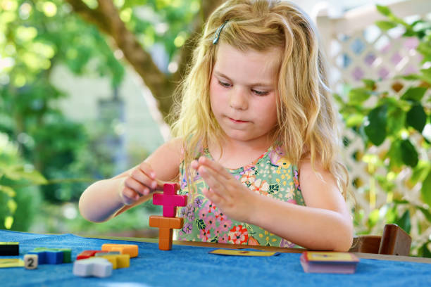 little preschool girl playing board game with colorful bricks. happy child build tower of wooden blocks, developing fine motor skills, home joint games. leisure activities for children at home. - jigsaw puzzle solution one person people imagens e fotografias de stock