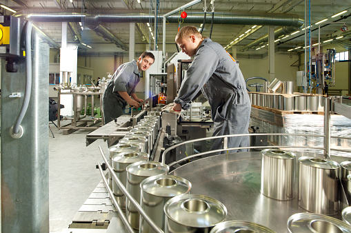 Two young workers working on an assembly line at a paint and varnish factory