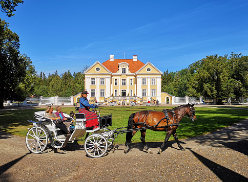 Palmse, Estonia - August 5, 2019: Horse carriage with tourists in front of Palmse manor building exterior on sunny summer day. Baroque style, 18th century.