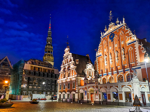 Riga, Latvia - August 6, 2019: City Hall Square with House of the Blackheads and Saint Peter church in Old Town of Riga at night, Latvia